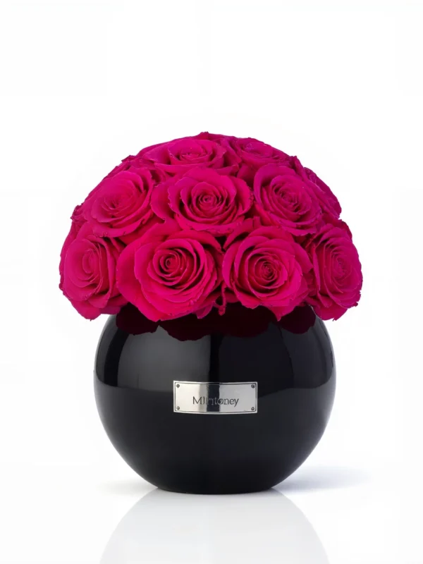 Round black Minoan Homey vase with vibrant pink roses, modern floral composition against white background