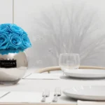 Minimalist dining setup with blue artificial roses and frosted glass panels