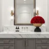 Modern bathroom with marble countertop, gold sconces, and red roses