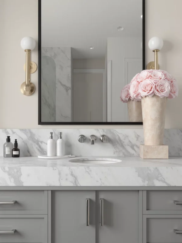 Modern bathroom with beige walls, gold sconces, and pink roses