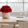 Elegant dining table with cream vase of red roses and winter view