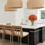 Modern kitchen with black island, woven pendant lights, and orange roses