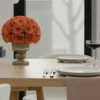 Minimalist dining setup with vase of orange-red roses and frosted window