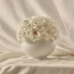 White vase with creamy white hydrangeas on draped fabric