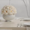 Elegant dining table with white vase of cream flowers and winter view