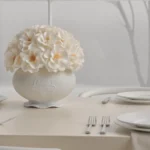 Elegant dining table with white vase of cream flowers and winter view