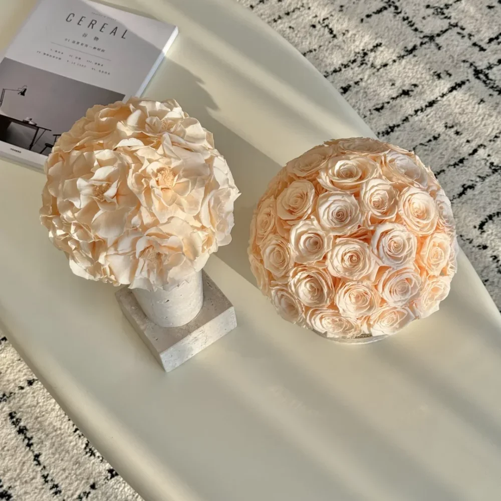 Minimalist interior with two ceramic vases of pale pink faux roses on sleek white oval table