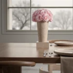 Minimalist dining setup with pink rose arrangement and wintery window view