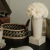 Minimalist interior with cream vase of white hydrangeas on marble stand