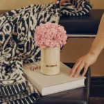 Hand placing blanket near vase with pink hydrangeas