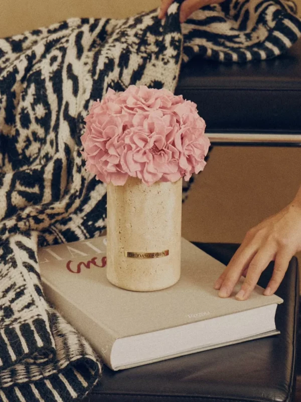 Hand placing blanket near vase with pink hydrangeas