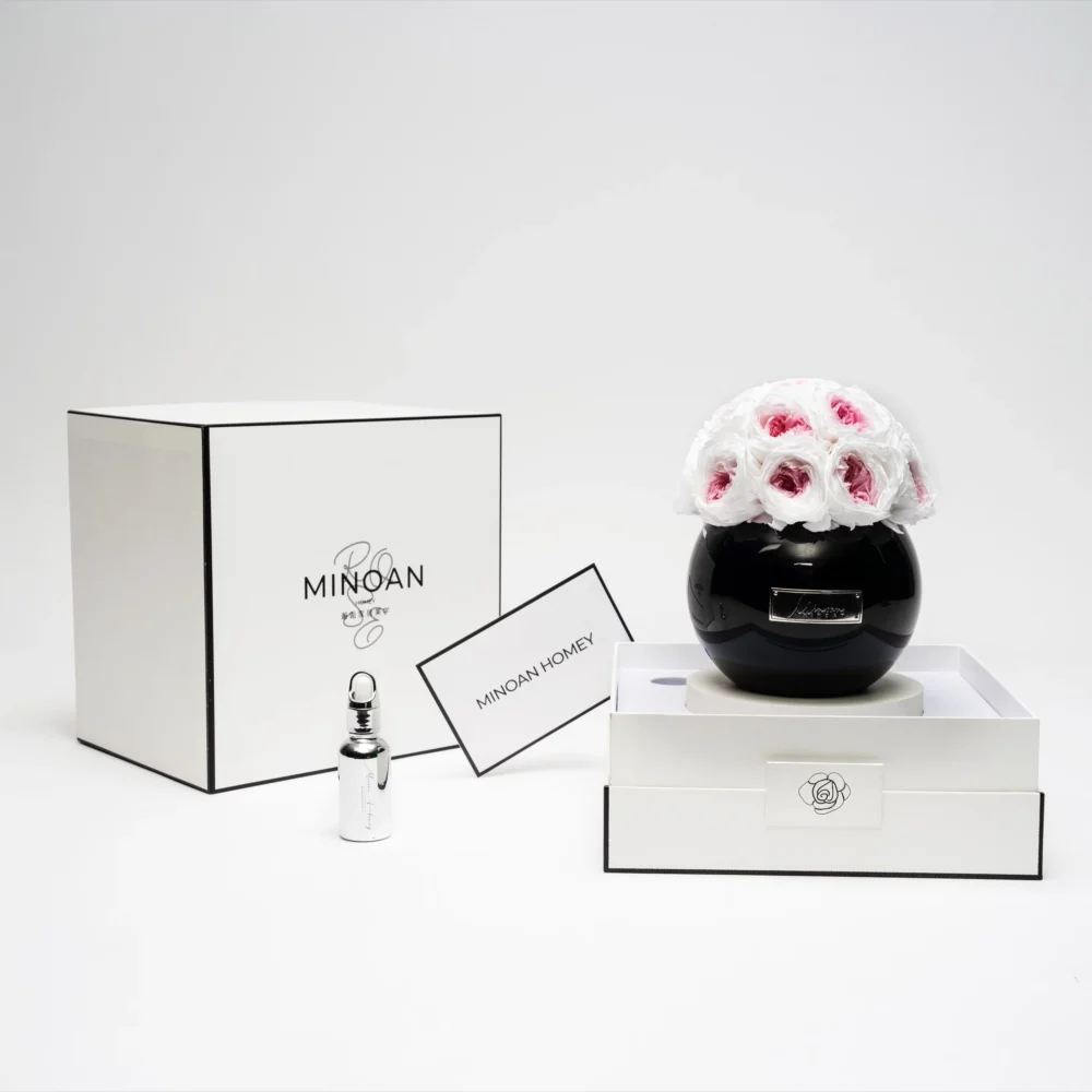 Minimalist elegant product display with black glass vase containing white roses with red tips and "Minox" branding