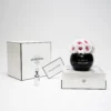 Minimalist elegant product display with black glass vase containing white roses with red tips and "Minox" branding