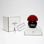 Luxurious minimalist setting with black vase of red roses and "Minoan" branded products on white studio setup
