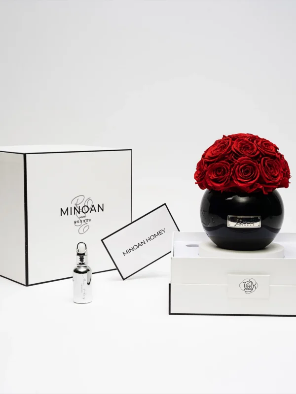 Luxurious minimalist setting with black vase of red roses and "Minoan" branded products on white studio setup