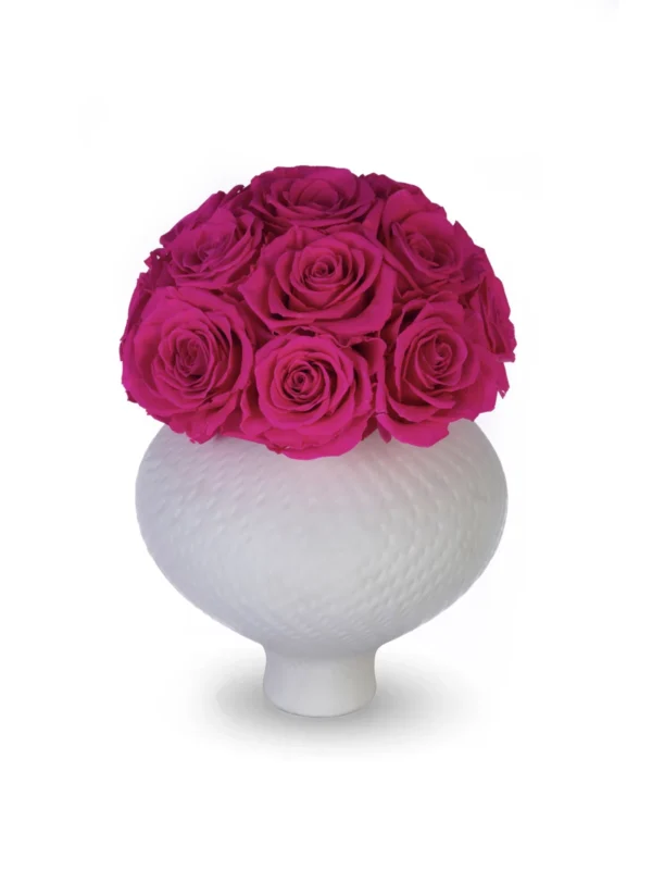 White ceramic honeycomb-pattern vase filled with dense cluster of vibrant deep magenta roses with velvety appearance