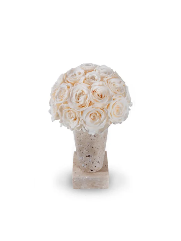 Decorative smooth pale beige stone vase containing lush bouquet of white roses on matching base against clean white