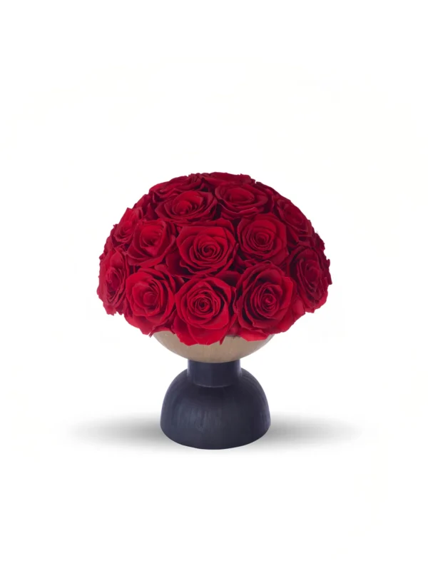 A photograph of a round, black pedestal vase holding a lush, vibrant bouquet of red roses. The roses are densely packed, with rich, velvety petals and dark green leaves peeking through. The vase is simple, modern, and sleek, with a matte finish. The background is stark white, creating a minimalist, elegant aesthetic that emphasizes the vivid red of the roses. The shadows cast by the vase and flowers are subtle, adding depth to the image.high quality, detailed, photograph , hd, 8k , 4k , sharp, highly detailed