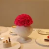 Elegant white ceramic vase with pink roses bouquet surrounded by ornate desserts