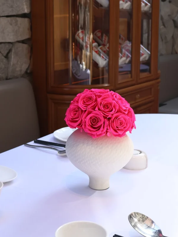 Formal table setting with white vase containing pink roses
