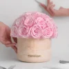 Pink rose bouquet in textured beige vase labeled "MINDAN HONEY" with hands holding white object