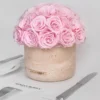 Round beige ceramic vase with pink roses and "MENDON HONEY" label alongside white plates