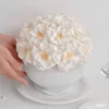 White ceramic bowl with lush white hydrangeas and embossed pattern held by hand