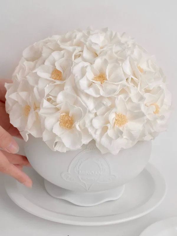 White ceramic bowl with lush white hydrangeas and embossed pattern held by hand