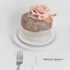 Two-tiered white and brown cake with pink rose and edible glitter on stand