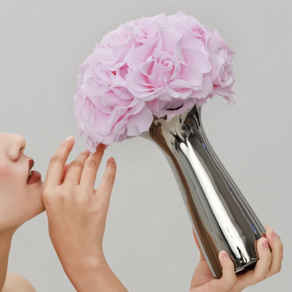 Close-up of woman holding silver vase with pink roses