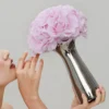 Close-up of woman holding silver vase with pink roses