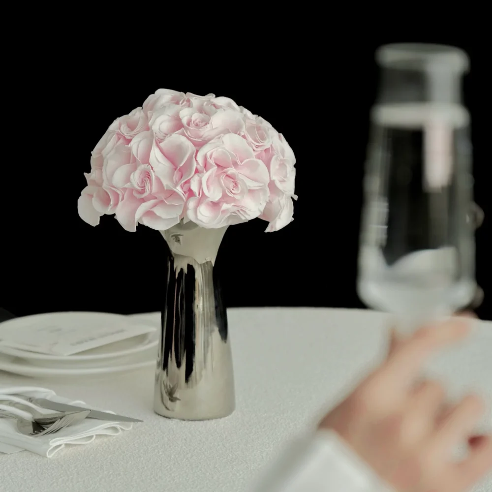 Pale pink roses in metallic vase with champagne glass