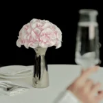Pale pink roses in metallic vase with champagne glass