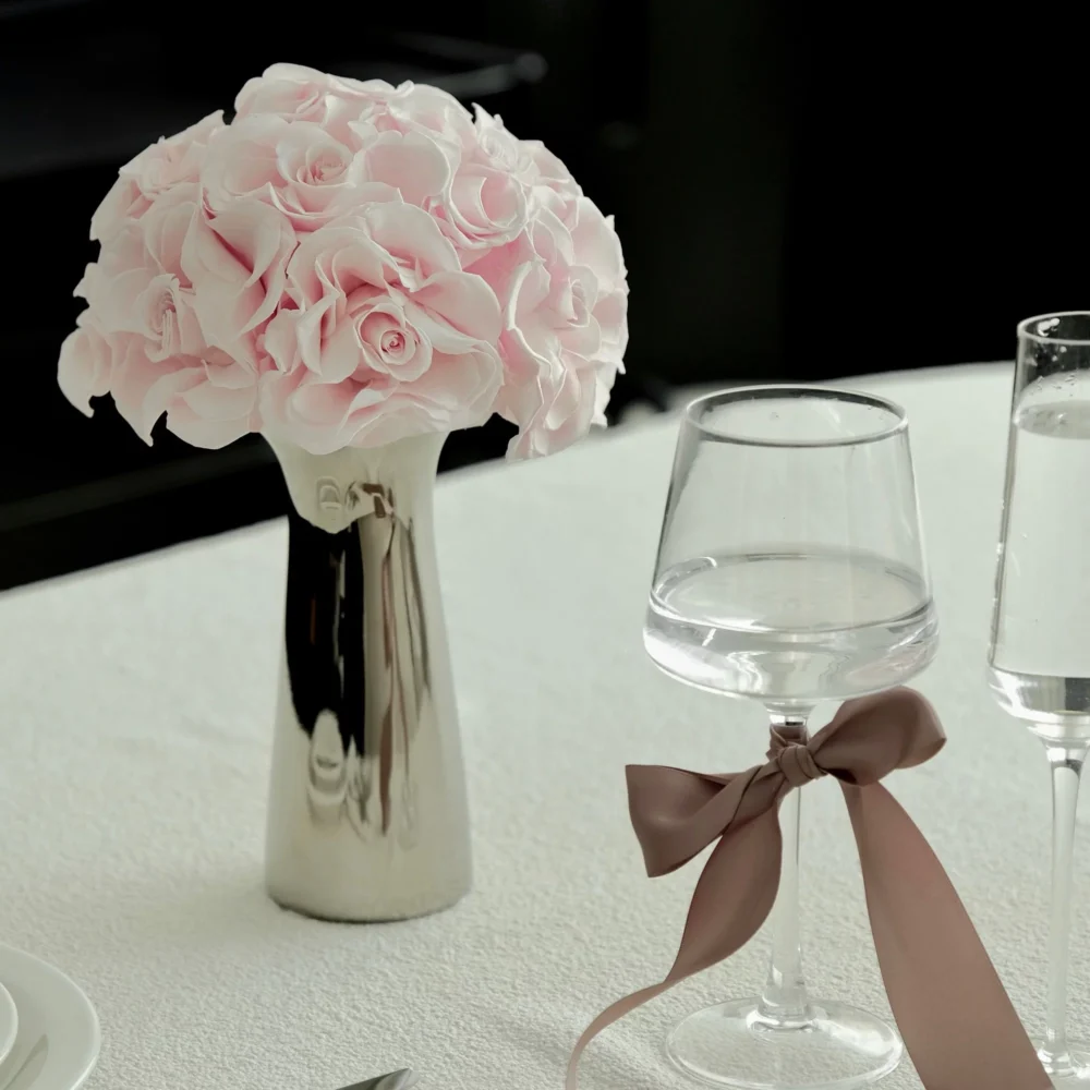 Minimalist table with metallic vase of pink roses and wine glasses