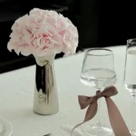 Minimalist table with metallic vase of pink roses and wine glasses