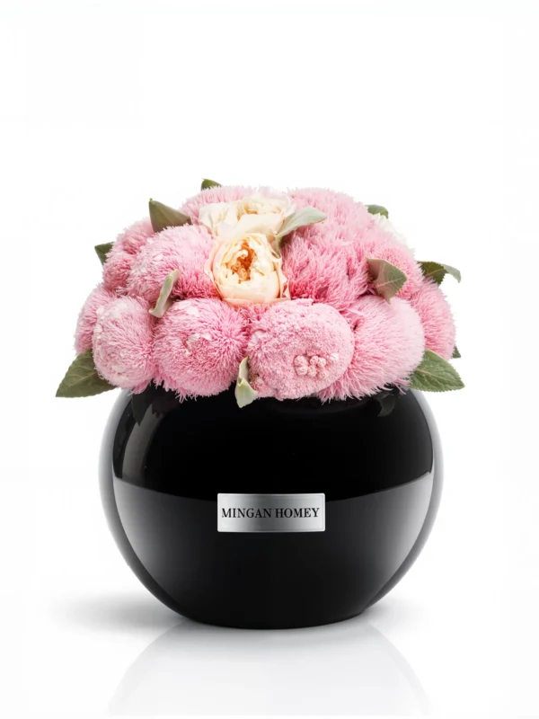 Glossy black Minoan Homey vase with pink chrysanthemums and peach roses, velvety floral arrangement