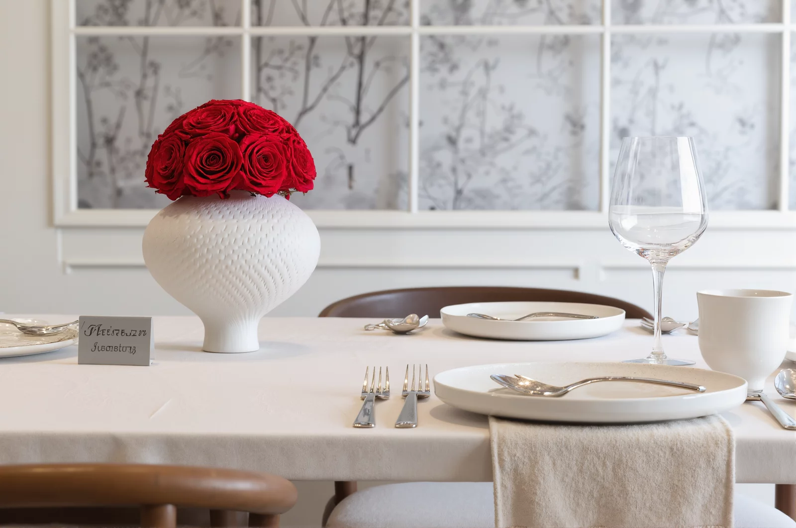 Minimalist dining table with white vase of red roses and floral wall art