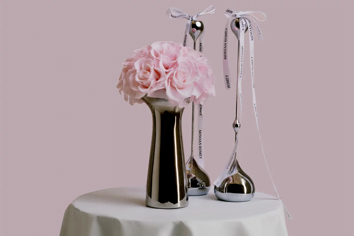 Minimalist elegant setup with shiny metallic vase of pink roses and silver wine glasses