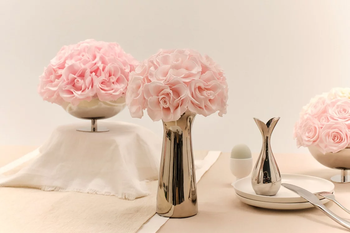 Elegant table with three vases of pink ruffled flowers
