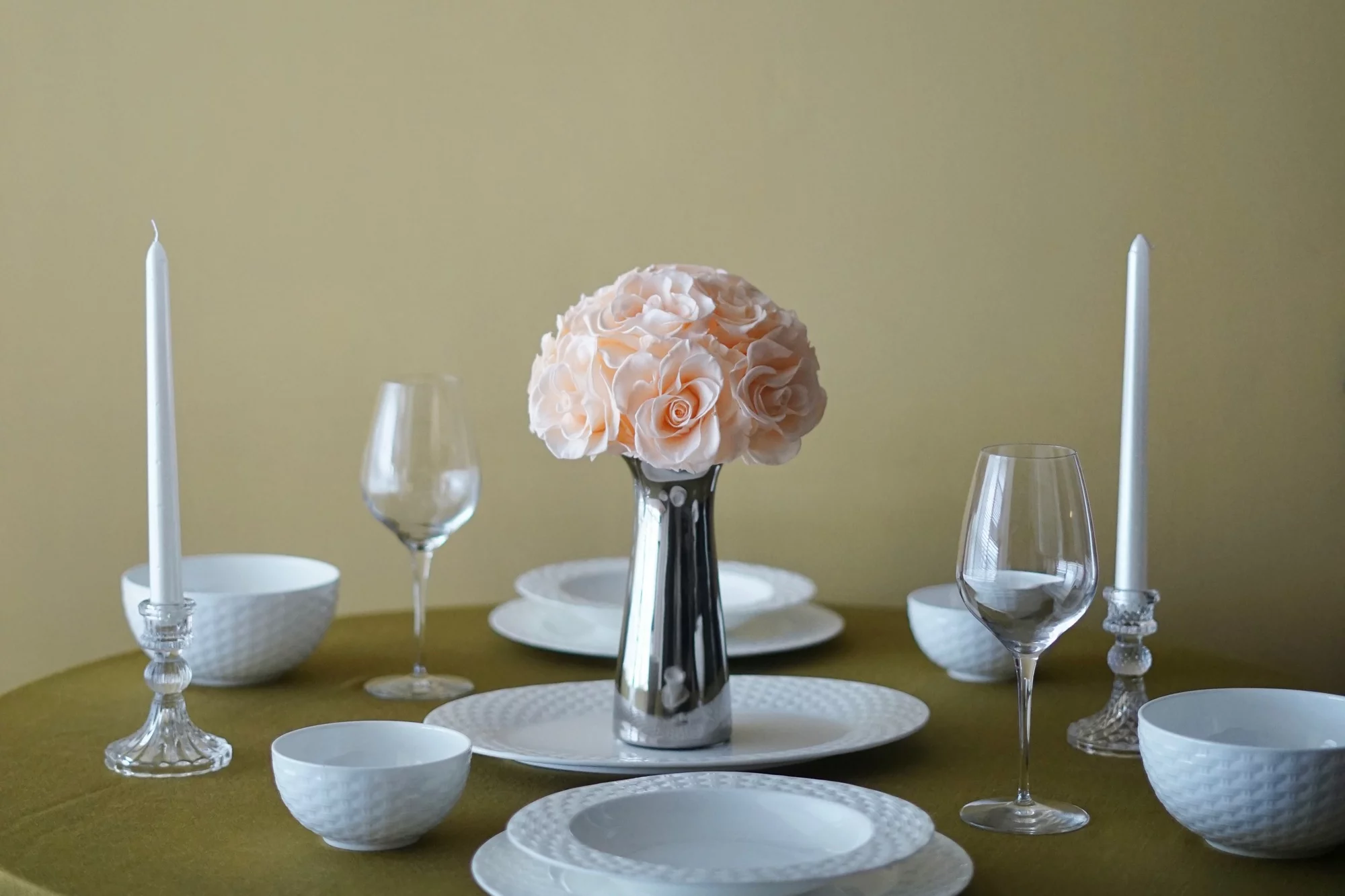 Minimalist table setting with olive green tablecloth and vase of pink roses
