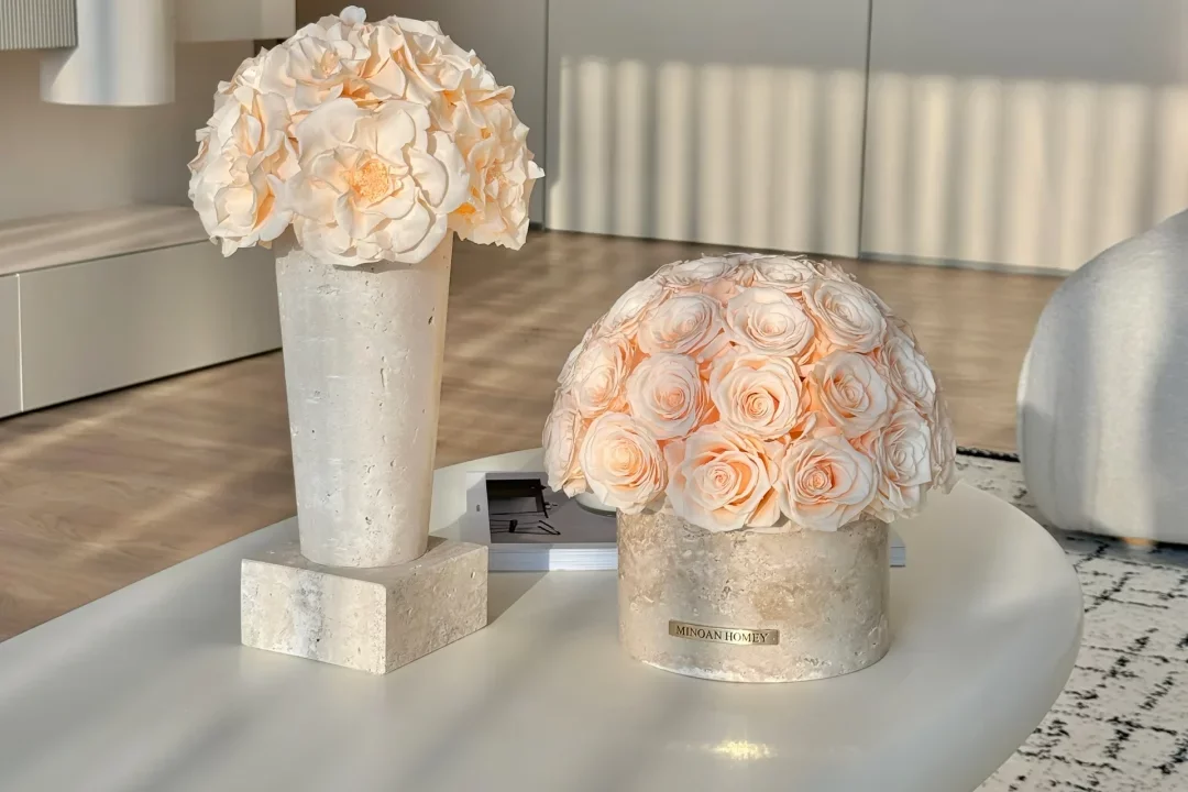 Modern minimalist living room with white oval coffee table and decorative vases holding white and peach roses
