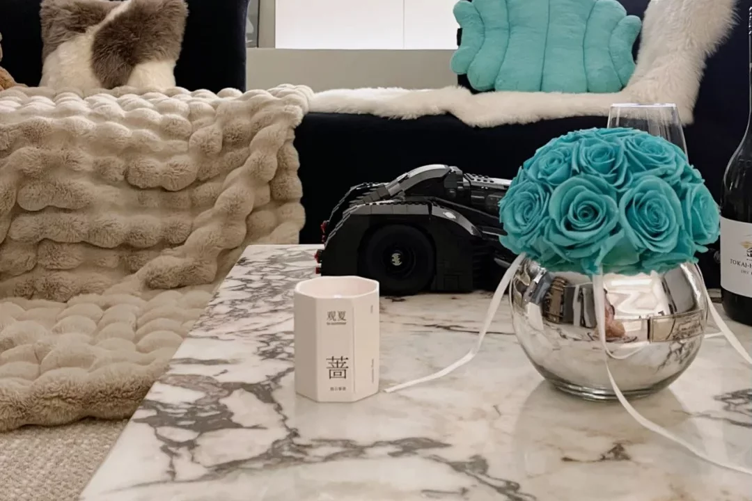 White marble coffee table with blue glass vase filled with turquoise roses in minimalist living room