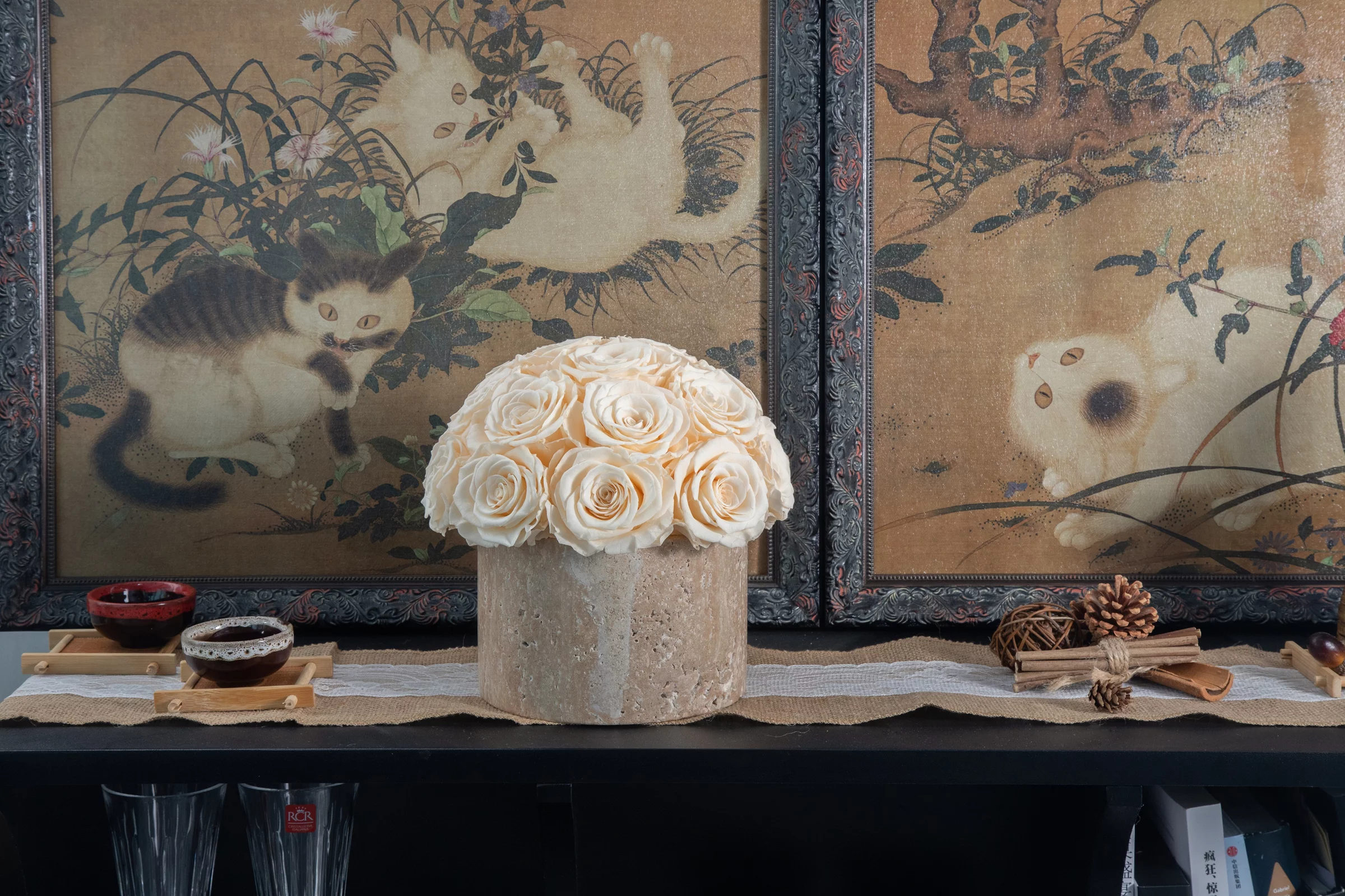 Decorative arrangement with beige vase holding elaborate white floral bouquet beside vintage-style paintings