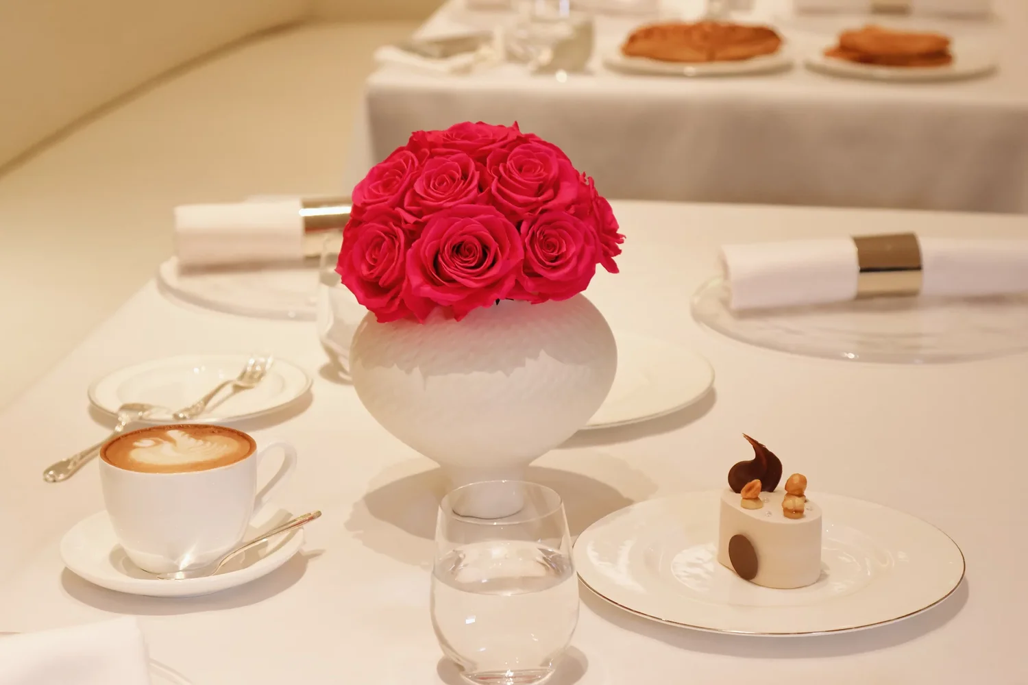 White textured ceramic vase with fuchsia pink roses bouquet in formal dining setting