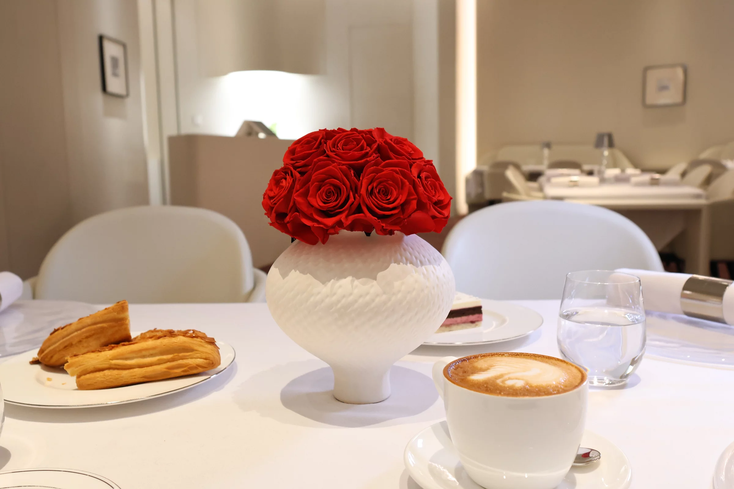 Sophisticated dining table with white ceramic vase holding red roses bouquet