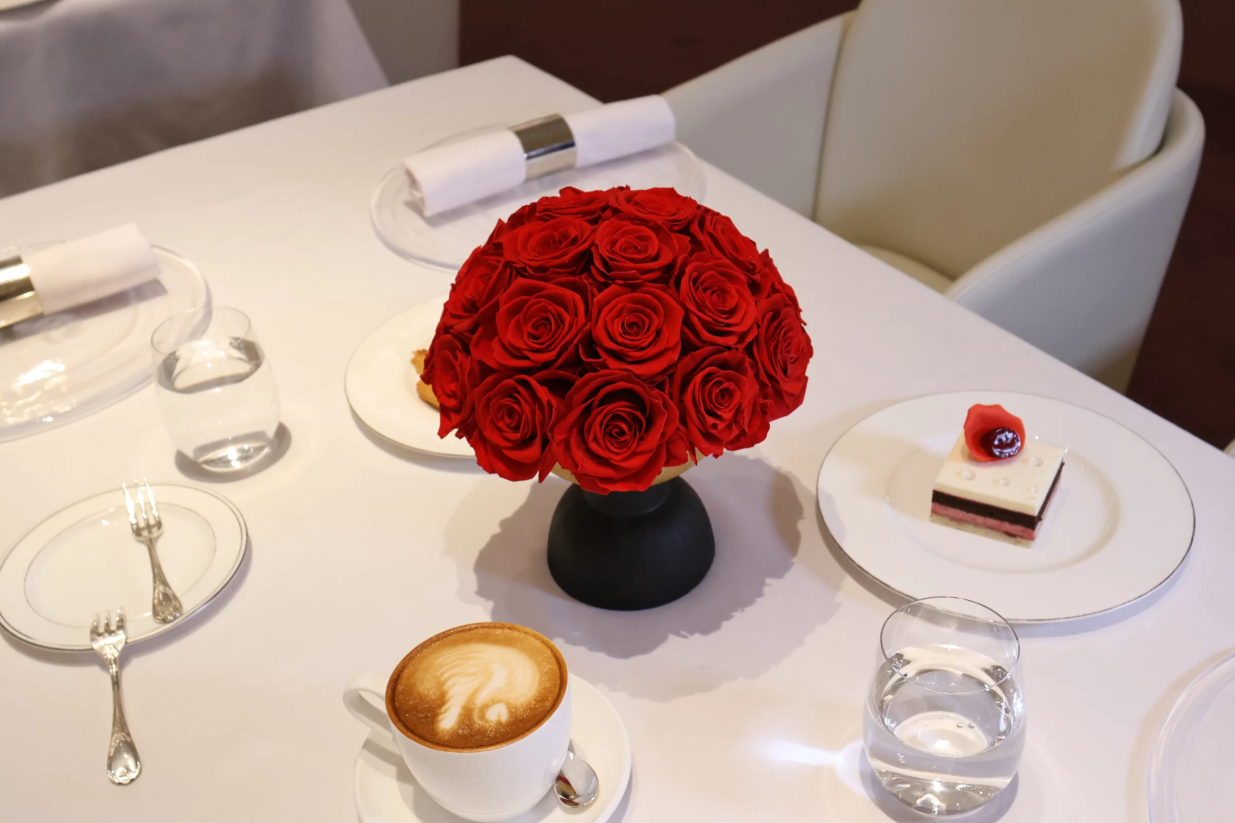 Neatly arranged table with black vase containing red roses bouquet