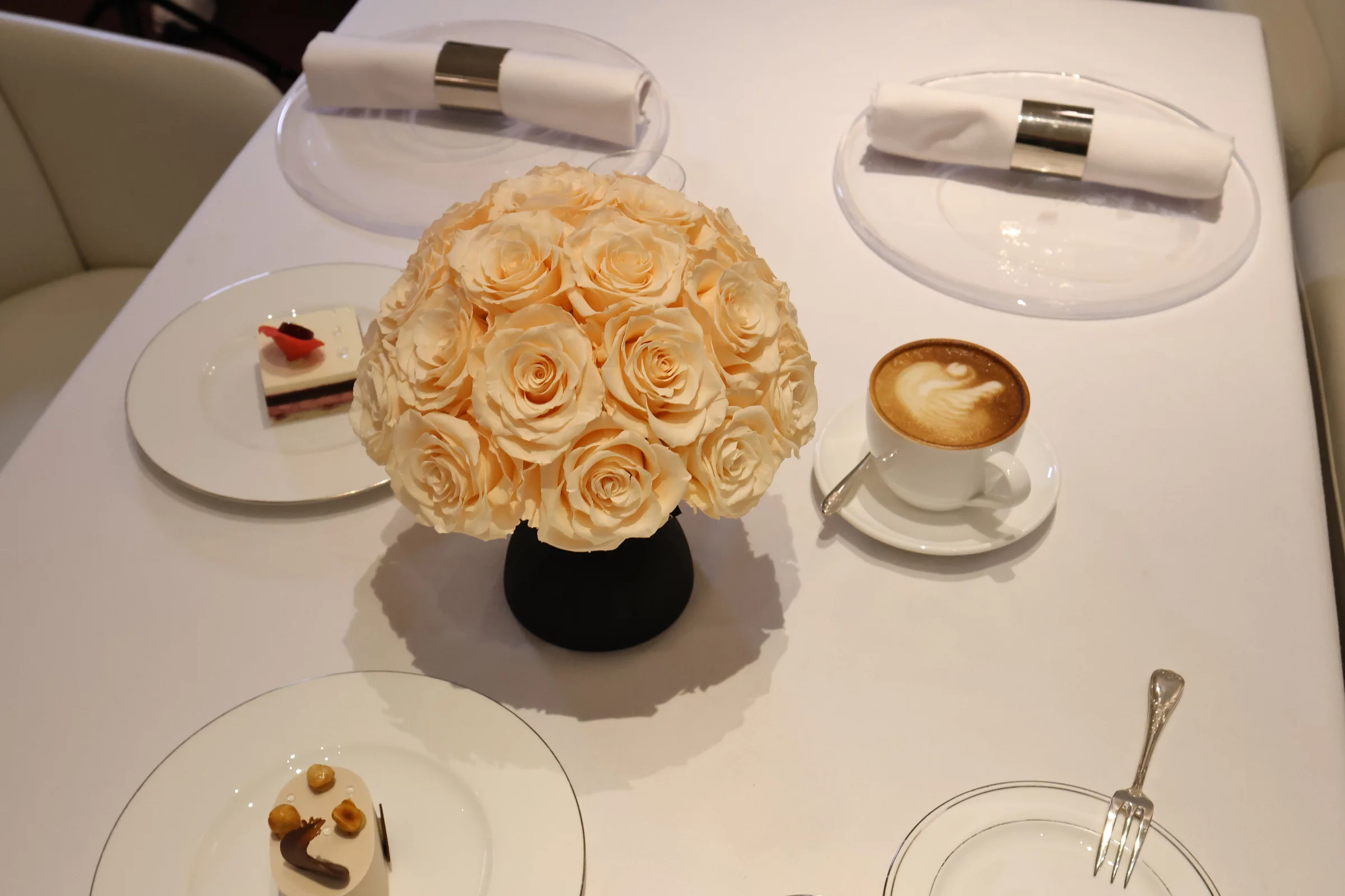 Black vase with cream roses bouquet and white napkins