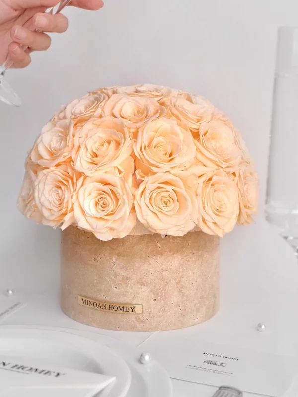 Cream spherical floral arrangement in beige vase with "MIDAS HONEY" label as hand pours water