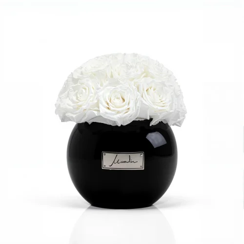 Luxury black ceramic vase with a refined cream lachaise label, showcasing pristine white roses in full bloom,