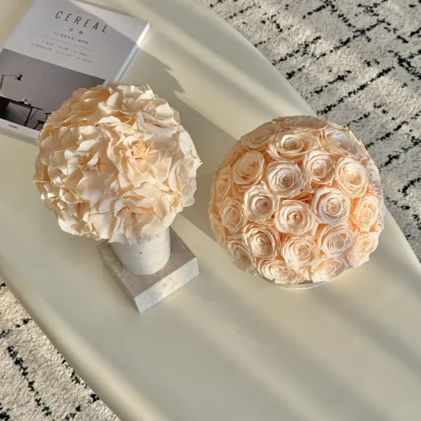 Minimalist interior with two ceramic vases of pale pink faux roses on sleek white oval table